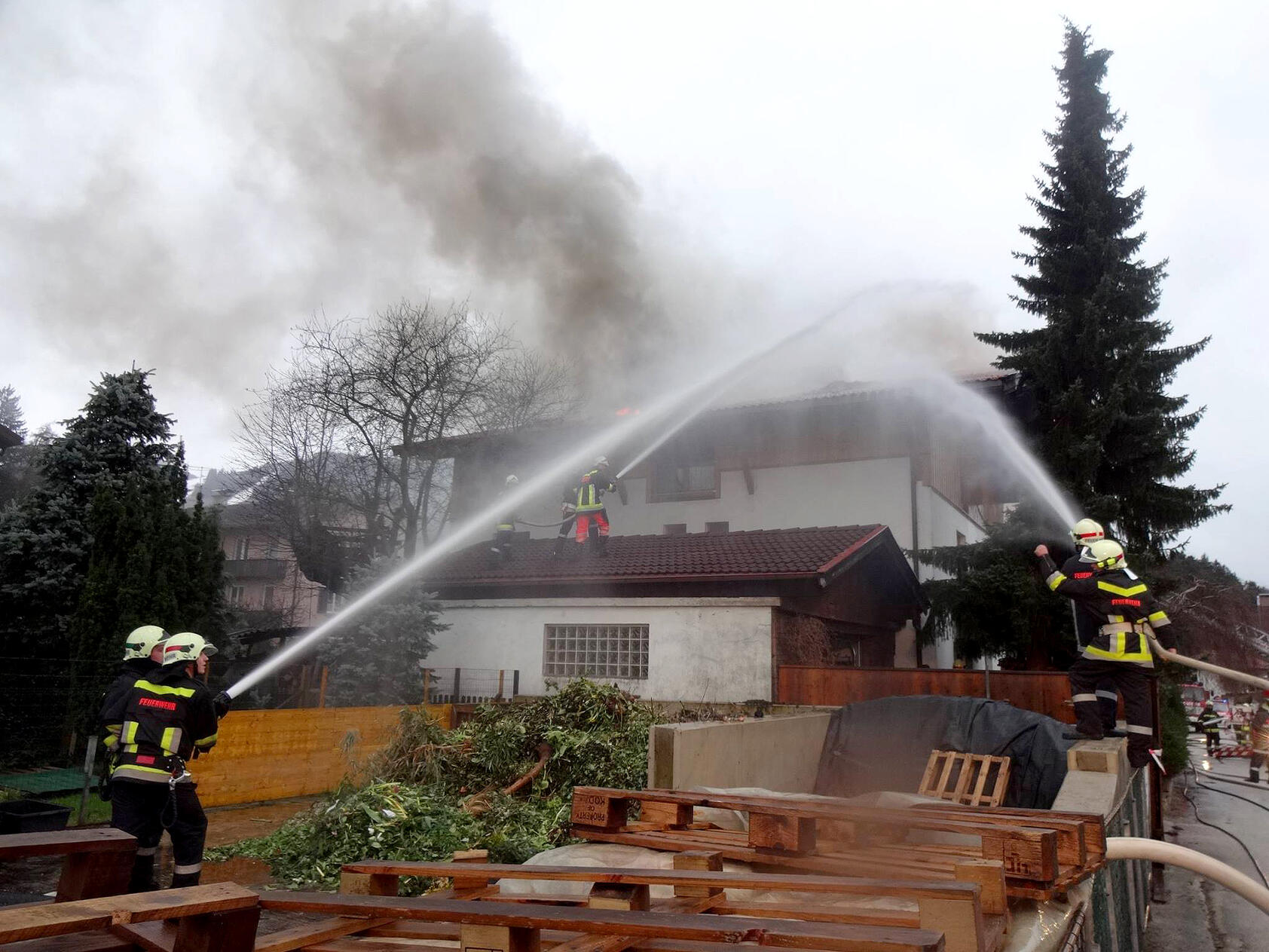 Wohnhausbrand mit löschender Feuerwehr